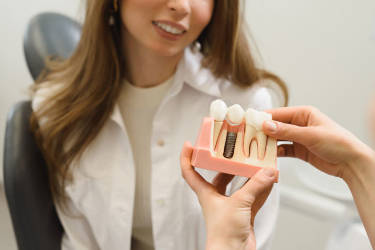 Dental Patient Getting Shown A Dental Implant Model During Her Consultation in Monroe, CT