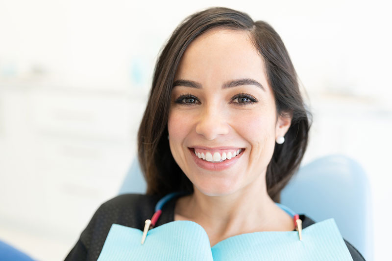 a full mouth dental implant patient smiling in a chair.